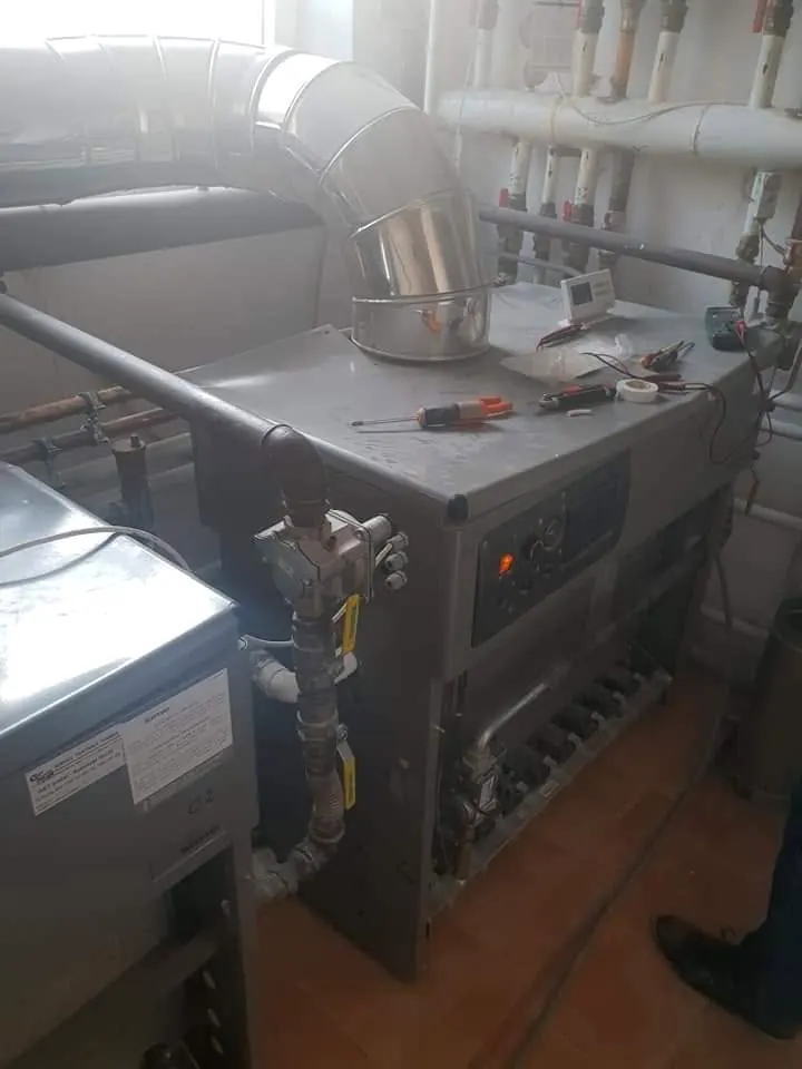 Cazan și distribuitor în camera tehnică a unei clădiri, în timpul montajului