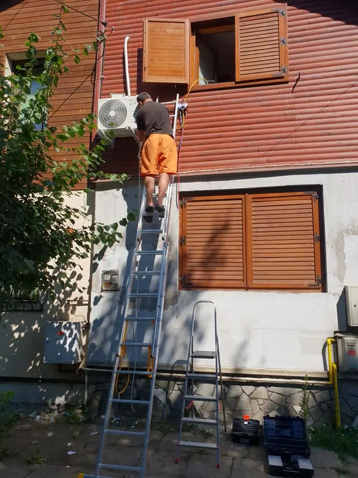 Montăm o unitate exterioară pe fațada unei case, de pe scară